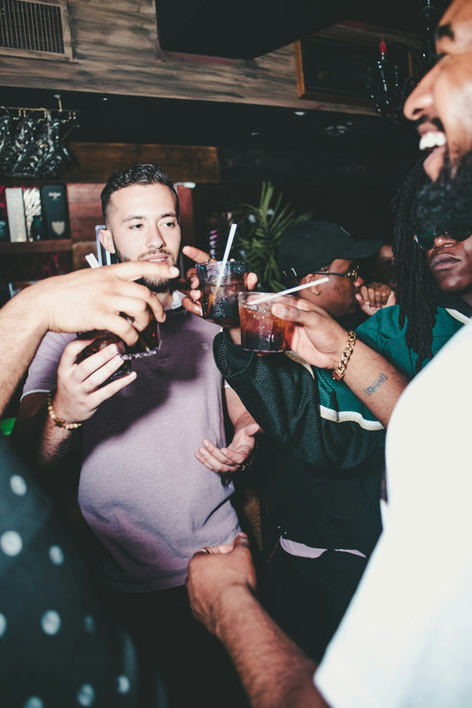 A group of people toasting with glasses of dark drinks in a bar