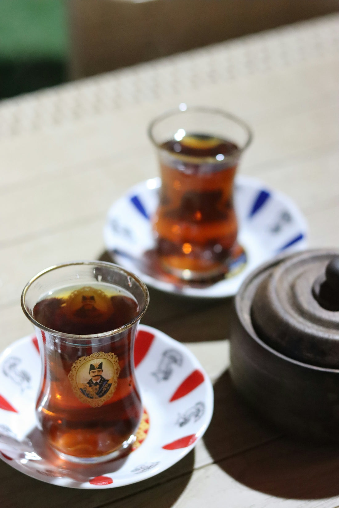 Two glasses of turkish tea are on a table.