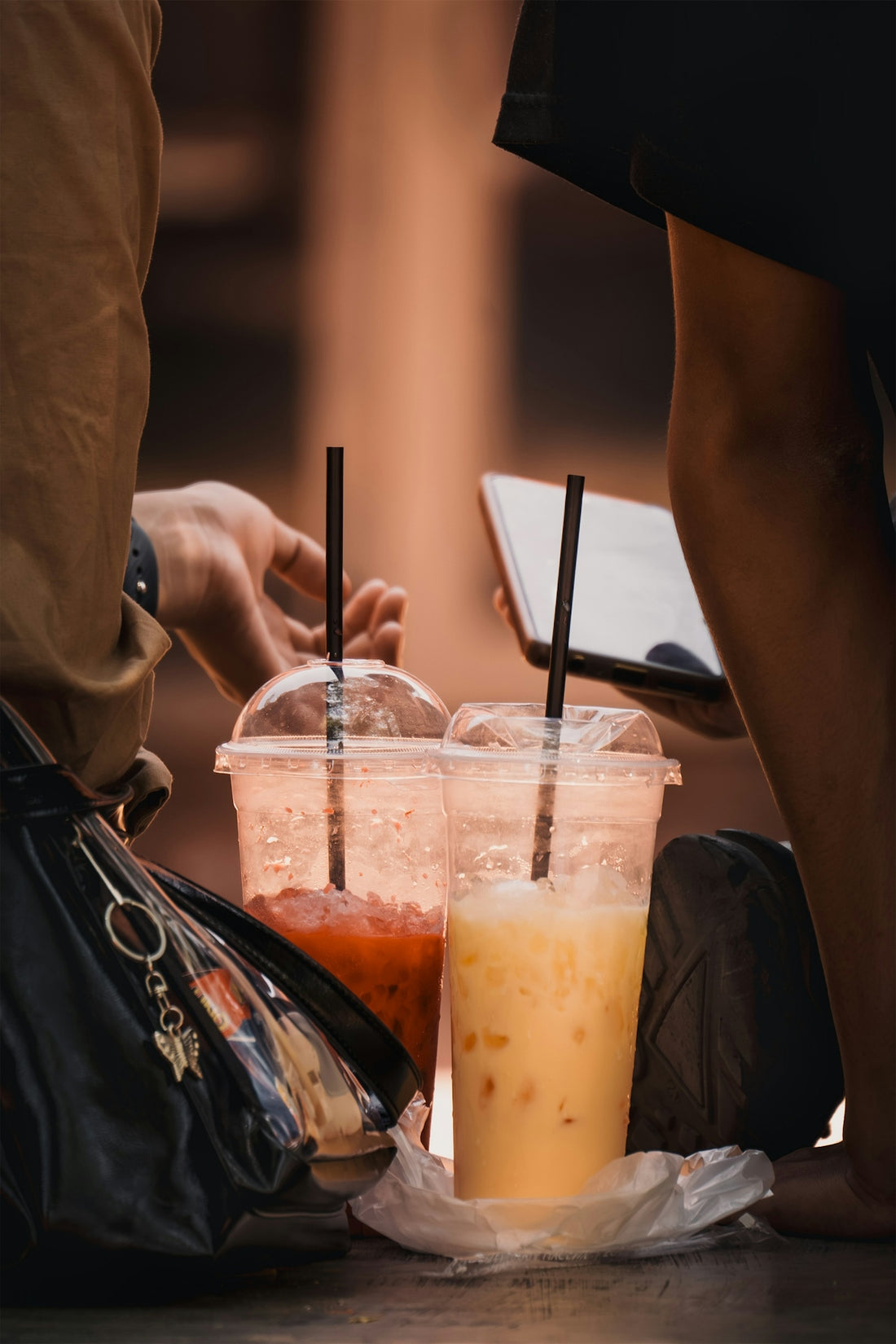 Two iced drinks with straws sit on the ground.